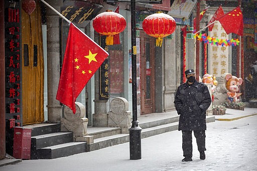 FILE - In this Feb. 5, 2020, file photo, a security guard wears a face mask as he walks along a pedestrian shopping street during a snowfall in Beijing. Skepticism about China&#146;s reported coronavirus cases and deaths has swirled throughout the crisis, fueled by official efforts to quash bad news in the early days and a general distrust of the government. In any country, getting a complete picture of the infections amid the fog of war is virtually impossible. (AP Photo/Mark Schiefelbein, File)