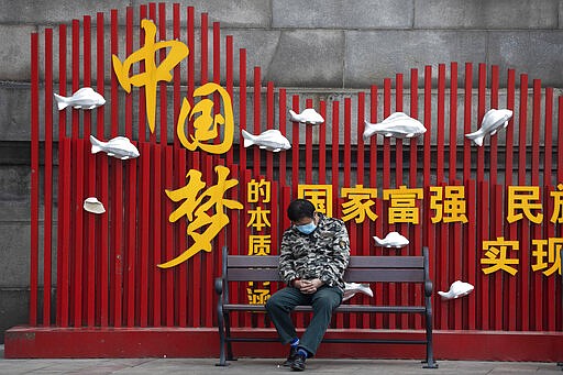 A resident naps near government propaganda which reads &quot;China Dream&quot; in Wuhan in central China's Wuhan province on Wednesday, April 1, 2020. Skepticism about China&#146;s reported coronavirus cases and deaths has swirled throughout the crisis, fueled by official efforts to quash bad news in the early days and a general distrust of the government. In any country, getting a complete picture of the infections amid the fog of war is virtually impossible. (AP Photo/Ng Han Guan)