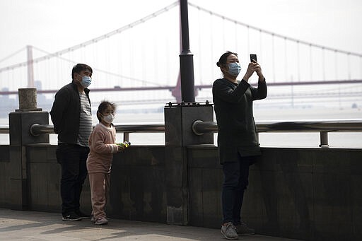 Residents walk along the banks of the Yangtze River in Wuhan in central China's Wuhan province on Wednesday, April 1, 2020. Skepticism about China&#146;s reported coronavirus cases and deaths has swirled throughout the crisis, fueled by official efforts to quash bad news in the early days and a general distrust of the government. In any country, getting a complete picture of the infections amid the fog of war is virtually impossible. (AP Photo/Ng Han Guan)