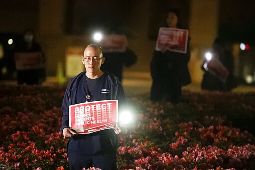 David Yamada, a nurse at UCLA Ronald Reagan Medical Center, participates in a vigil in Los Angeles, Monday, March 30, 2020. The vigil was put on to celebrate the steps that have been made at the medical center in protecting nurses' health and safety during the COVID-19 outbreak, and to call on further action from the federal government and demand additional improvements for nurses everywhere. (AP Photo/Chris Carlson)