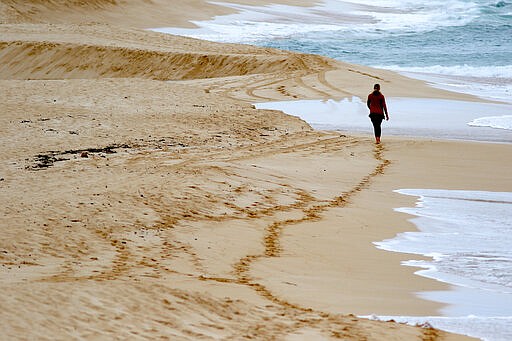 A woman walks on an empty beach on Oahu's North Shore near Haleiwa, Hawaii, Tuesday, March 31, 2020. Hawaii Gov. David Ige is further tightening travel restrictions to limit the spread of the coronavirus by ordering people moving between islands to adhere to a 14-day self-quarantine. The order takes effect at midnight on Wednesday. It won't apply to essential workers like health care workers traveling to other islands.&#160;The order comes a week after the governor ordered everyone arriving in the state from other states or overseas to follow the same two-week quarantine. He's also ordered everyone in the state to stay at home for the next month.&#160;(AP Photo/Caleb Jones)