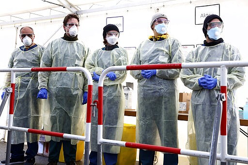 FILE - In this March 23, 2020, file photo, medical employees wait to carry out tests at a coronavirus test center for public service employees, during a media presentation in Munich, Germany. Germany has seen a steady rise in the number of new coronavirus infections, but so far deaths have been low compared to many of its European neighbors. (AP Photo/Matthias Schrader, File)