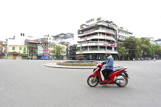A motorcyclist drives on a quiet street in Hanoi, Vietnam, Wednesday, April 1, 2020. Vietnam on Wednesday starts two weeks of social distancing to contain the spread of COVID-19. The new coronavirus causes mild or moderate symptoms for most people, but for some, especially older adults and people with existing health problems, it can cause more severe illness or death. (AP Photo/Hau Dinh)