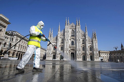 A worker sprays disinfectant to sanitize Duomo square, as the city main landmark, the gothic cathedral, stands out in background, in Milan, Italy, Tuesday, March 31, 2020. The new coronavirus causes mild or moderate symptoms for most people, but for some, especially older adults and people with existing health problems, it can cause more severe illness or death. (AP Photo/Luca Bruno)