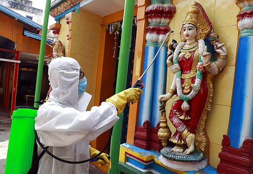 A member of the military wearing full protective gear sprays disinfectant at a Hindu temple to help curb the spread of the new coronavirus in Naypyitaw, Myanmar, Wednesday, April 1, 2020. The new coronavirus causes mild or moderate symptoms for most people, but for some, especially older adults and people with existing health problems, it can cause more severe illness or death. (AP Photo/Aung Shine Oo)