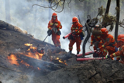 In this photo released by Xinhua News Agency, firefighters put out a forest fire in Xichang, in southwestern China's Sichuan Province, Tuesday, March 31, 2020. Nineteen people have died while fighting a raging forest fire in southwestern China and hundreds of reinforcements were sent to fight the blaze and evacuate nearby residents, officials and state media reported Tuesday. (Li Jieyi/Xinhua via AP)