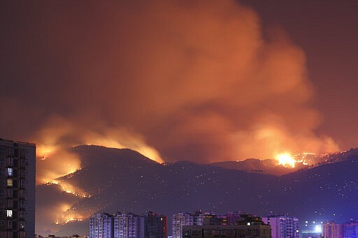 In this photo released by Xinhua News Agency, forest fire burn near residential buildings in Xichang, in southwestern China's Sichuan Province, on Tuesday, March 31, 2020. Nineteen people have died while fighting a raging forest fire in southwestern China and hundreds of reinforcements were sent to fight the blaze and evacuate nearby residents, officials and state media reported Tuesday. (Liu Mingke/Xinhua via AP)