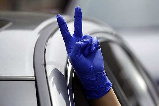 A protester flashes a peace sign during a car-based protest outside the Edward R. Roybal Federal Building Tuesday, March 31, 2020, in Los Angeles. Demonstrators across California coordinated efforts in a car-based protest to demand the release of immigrants in California detention centers over concerns over the COVID-19 pandemic. (AP Photo/Marcio Jose Sanchez)