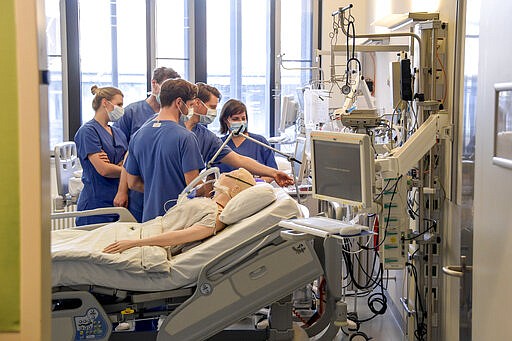 In this Tuesday, March 25, 2020, photo, hospital doctors get instructions on a ventilator at the University Hospital Eppendorf in Hamburg Germany. Germany has seen a steady rise in the number of new coronavirus infections, but so far deaths have been low compared to many of its European neighbors.  (Axel Heimken/Pool Photo via AP)