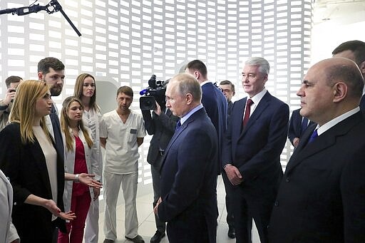 In this photo taken on Tuesday, March 17, 2020, Russian President Vladimir Putin, center, Prime Minister Mikhail Mishustin, right, and Moscow Mayor Sergei Sobyanin, second right, listen to employees of a call center of the emergency response center on control and monitoring of the coronavirus disease, in Moscow, Russia. Russian authorities declared a war on &quot;fake news&quot; related to the new coronavirus. The crusade was triggered by what looked like a real disinformation campaign, but as the outbreak in Russia picked up speed and criticism of the Kremlin's &quot;it is under control&quot; stance mounted, the authorities cracked down on social media users doubting the official numbers and news outlets questioning the government's response to the epidemic. (Mikhail Klimentyev, Sputnik, Kremlin Pool Photo via AP)