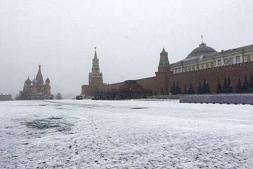 Municipal workers clean an almost empty Red Square, with St. Basil's Cathedral, center, and Spasskaya Tower and the Kremlin Wall, at right, during light snowfall in Moscow, Russia, Tuesday, March 31, 2020. Moscow Mayor Sergei Sobyanin followed up by ordering Muscovites to stay home starting Monday except for medical emergencies and runs to nearby shops. The new coronavirus causes mild or moderate symptoms for most people, but for some, especially older adults and people with existing health problems, it can cause more severe illness or death. (AP Photo/Dmitry Kozlov)