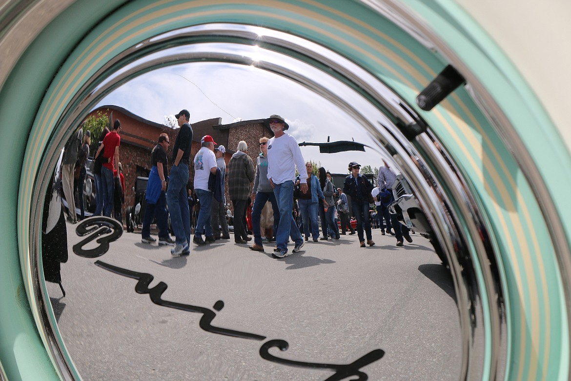 A few of the thousands of classic car fans and owners who turned out for a past Lost in the '50s are seen reflected in the hubcap of a classic Buick. The event returns the third weekend in May after a two-year absence caused by the COVID-19 pandemic. More than 700 cars are expected to take part in the event.