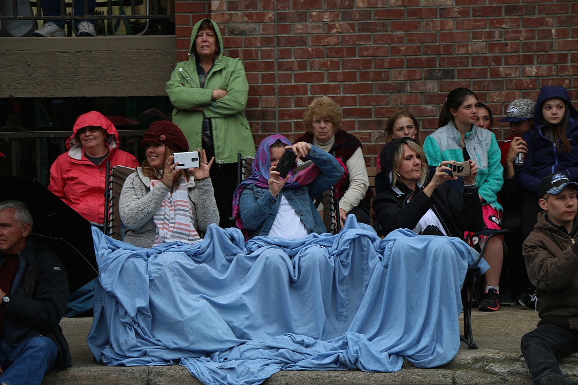 &#151;Photo by CAROLINE LOBSINGER
Parade-goers grab their phones to catch the classic cars driving by on First Avenue during Friday&#146;s Lost in the &#145;50s parade.