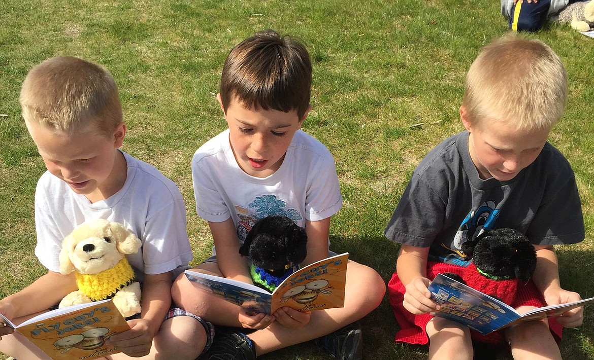 -- Photo courtesy KYLA FRENCH

First grade students Wyatt Mujo, Hudson Brown and Mason Shaffer, left to right, and their puppies -- wearing hand-knit sweaters -- read together in the grass.