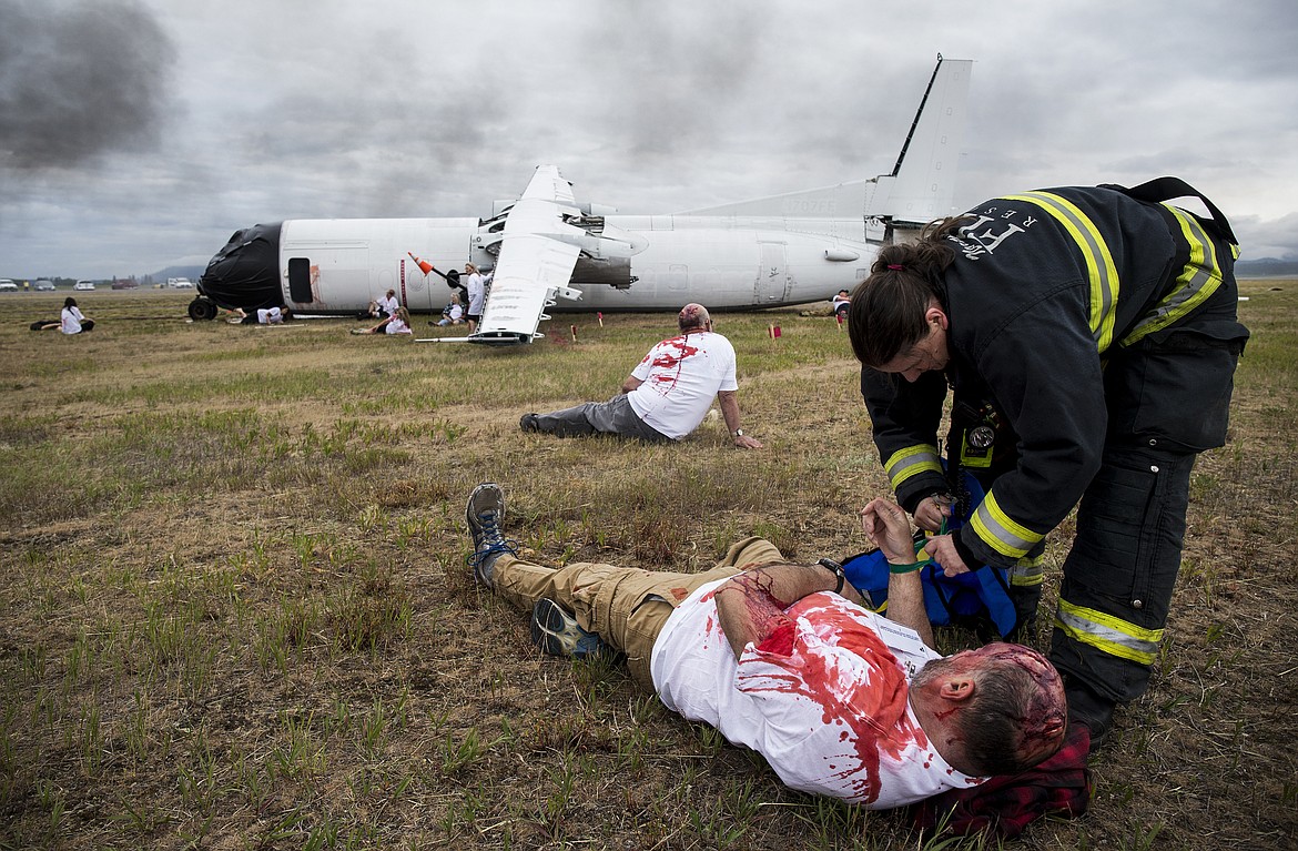 LOREN BENOIT/PressAmanda Tams of Northern Lakes Fire and Rescue wraps a  green wristband around a plane crash victim during a training exercise at the Coeur d'Alene Airport on Friday.  24 passengers were injured in the two-plane crash and 6 fatalities were reported. The injured were taken to Kootenai Health for treatment.