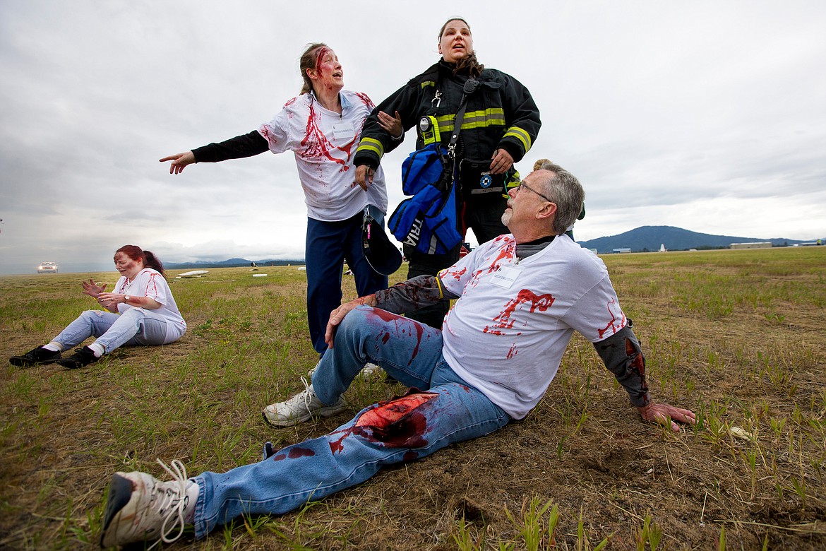 JAKE PARRISH/PressNorthern Lakes firefighter Amanda Tams surveys a mock plane crash scene on Friday as crash &quot;victims&quot; act out at the Coeur d'Alene Airport.