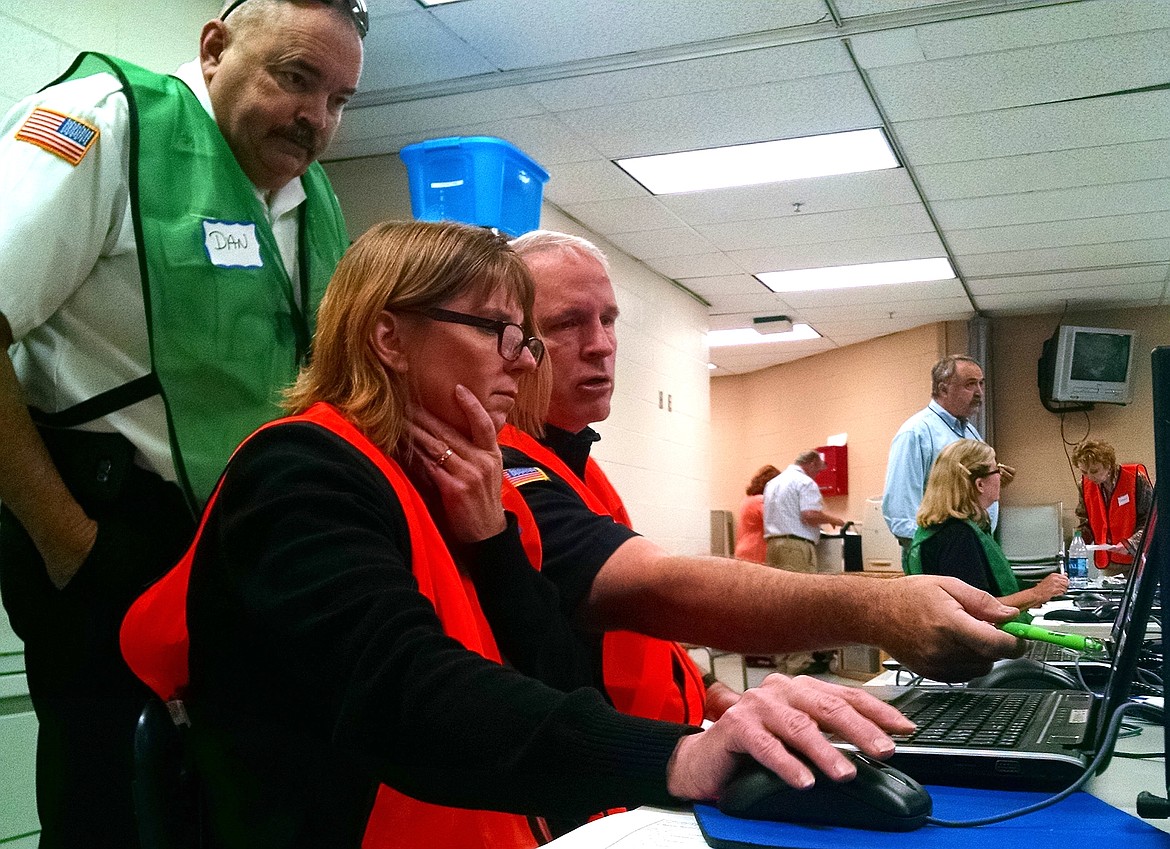 BRIAN WALKER/Press
Dan Ryan, left, of Kootenai County Fire and Rescue, looks over the shoulders of Kimberly Hobson, deputy public information officer, and Jim Lyon, chief PIO, as a press release is prepared at the emergency operations center at the Kootenai County Sheriff's Office on Thursday.