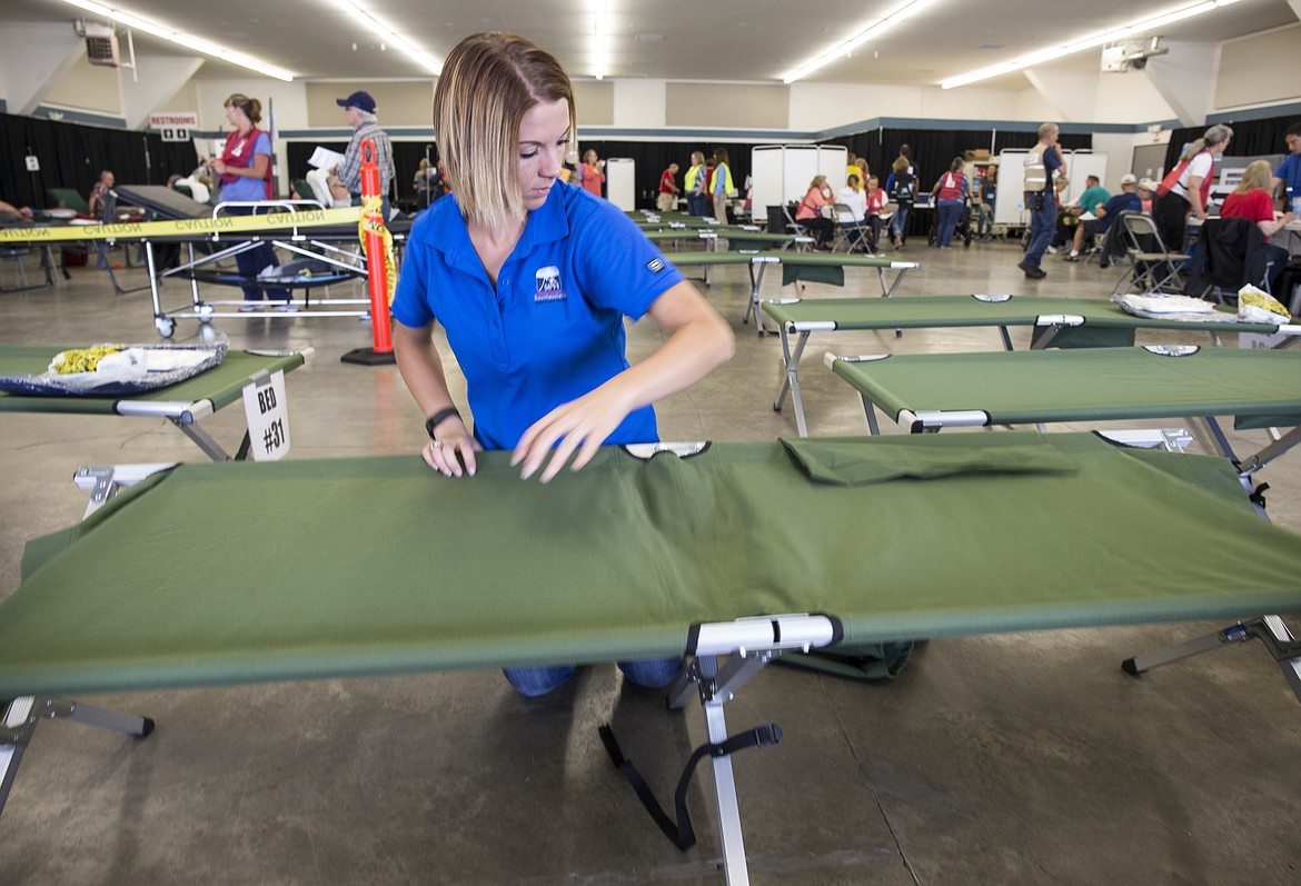 LOREN BENOIT/Press
Mandi Nelson of SouthEastern Idaho Public Health Region 6 sets up an Army cot on Thursday at the Kootenai County Fairgrounds in Coeur d'Alene.