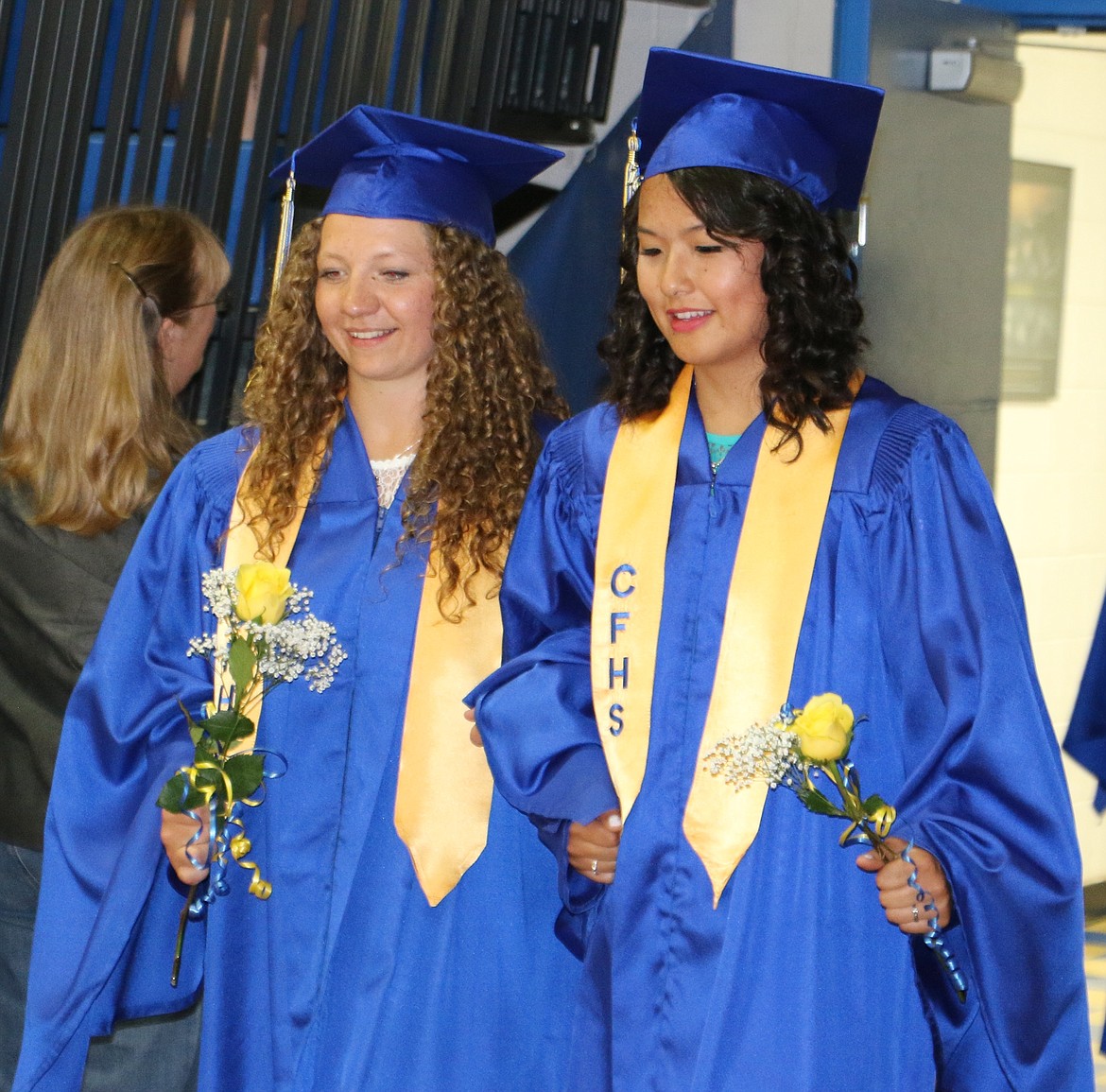 -- Photo by LYNNE HALEY

Leslie Kiebert, left, and Rose Wu Levy, right, enter the Clark Fork gym on their graduation night. The graduates carried yellow rose bouquets they later gave to their parents.