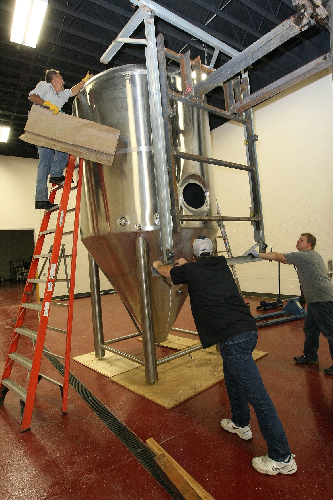 Owner Fred Colby, middle, along with son Devon Colby, right and John Vitale, pull the moving frame back from one of the fermenters in the new facility after moving it from the old facility.

&#151;Photo by JIM McKIERNAN