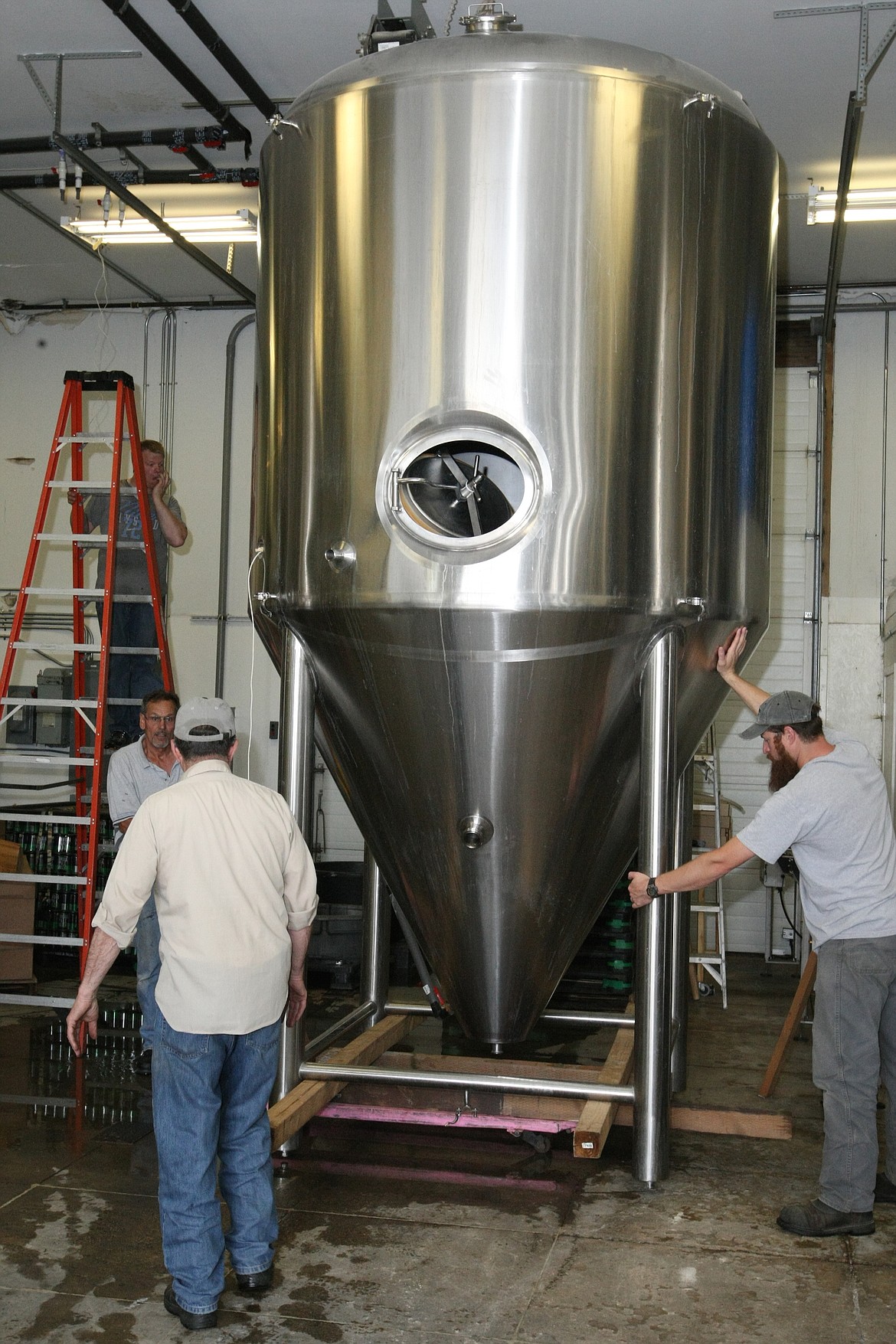 &#151;Photo by JIM McKIERNAN
Head Brewer Eric Burg, right) steadys one of the 30 barrel fermenters as Carl Quass, center and John Vitale lower the pallet jack. Devon Colby, on the ladder watches overhead clearance.