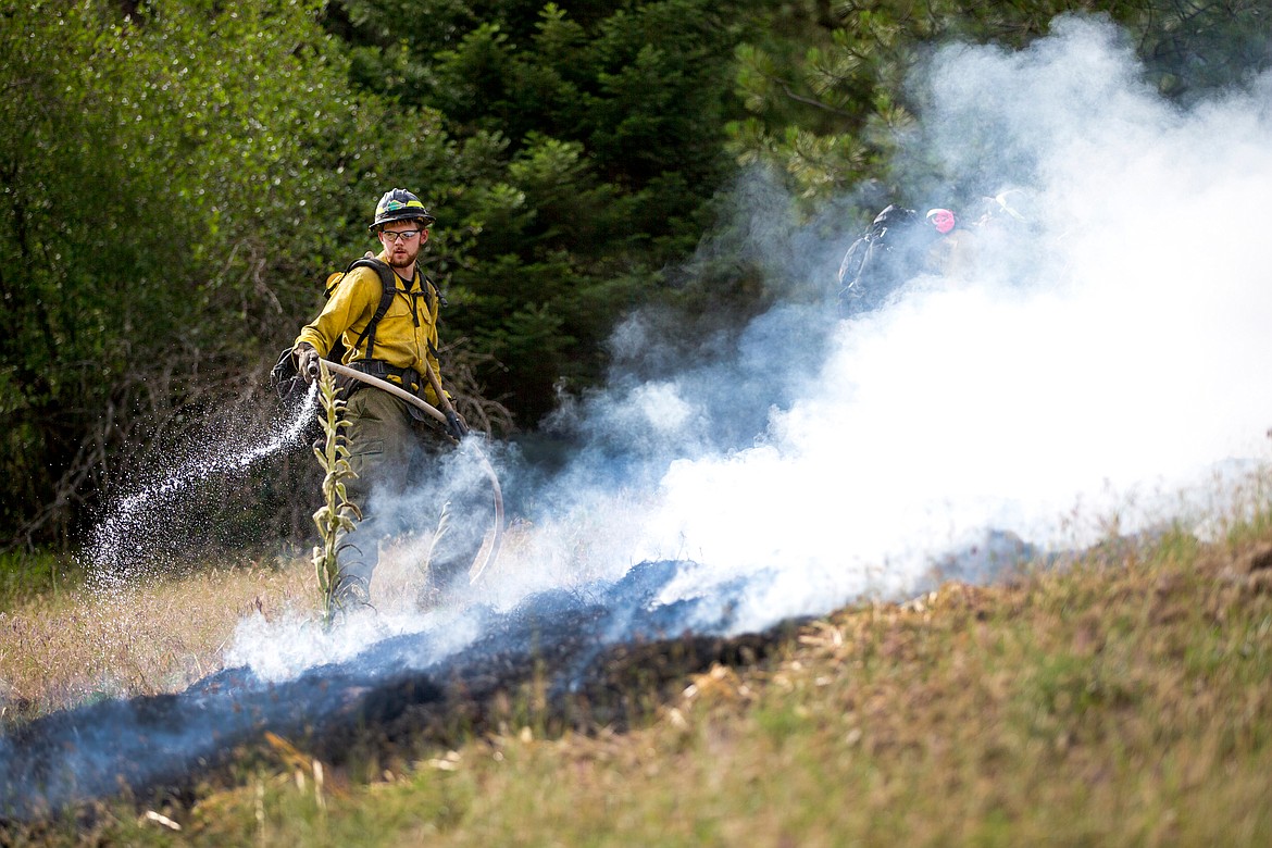 JAKE PARRISH/PressIdaho Department of Lands firefighter Mark Maret sprays water along the perimeter of a controlled burn during a demonstration on Thursday at the Funk Family Tree Farm in Wolf Lodge. The demonstration, put on by the Mica Fire Protection District and the Idaho Forest Products Commission, was aimed to show educators in the area how wildland firefighters operate.