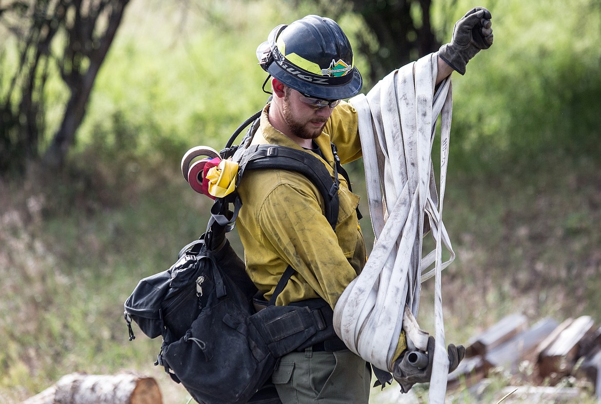 KATIE HARTWIG/Presswraps up hose after containing fire for the demonstration, Thursday at Wolf Lodge.