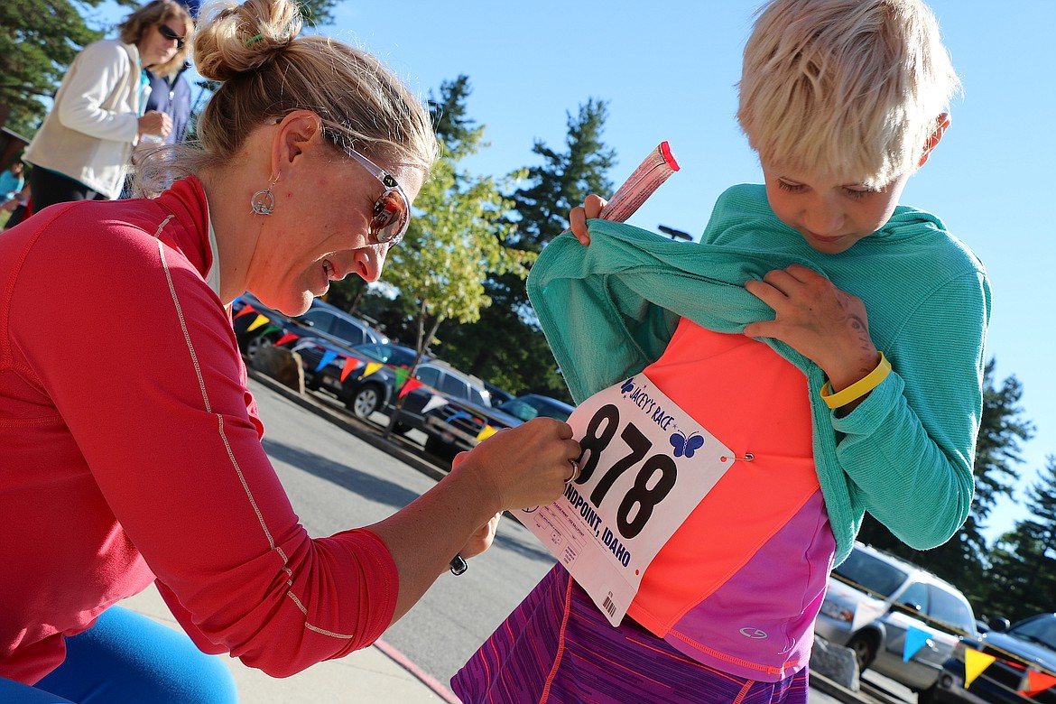 &#151;Photo by CAROLINE LOBSINGER
Ammi Midstokke pins a racing big on her daughter, Beverly as the duo get ready to take part in Jacey's Race on Sunday.