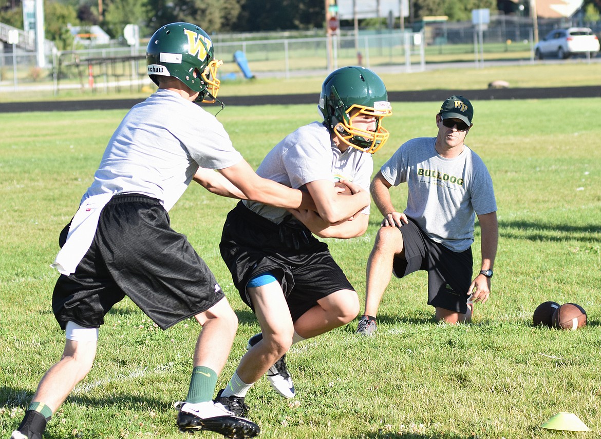 Running backs take hand-offs at practice Friday.