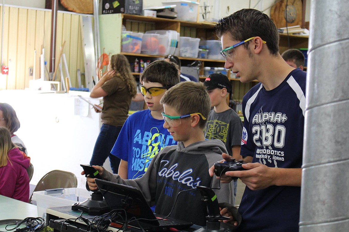 -- Photo courtesy JILL KATZ
Brodie Becker and Luke Smith receive robot driving directions from mentor Neil Martin.