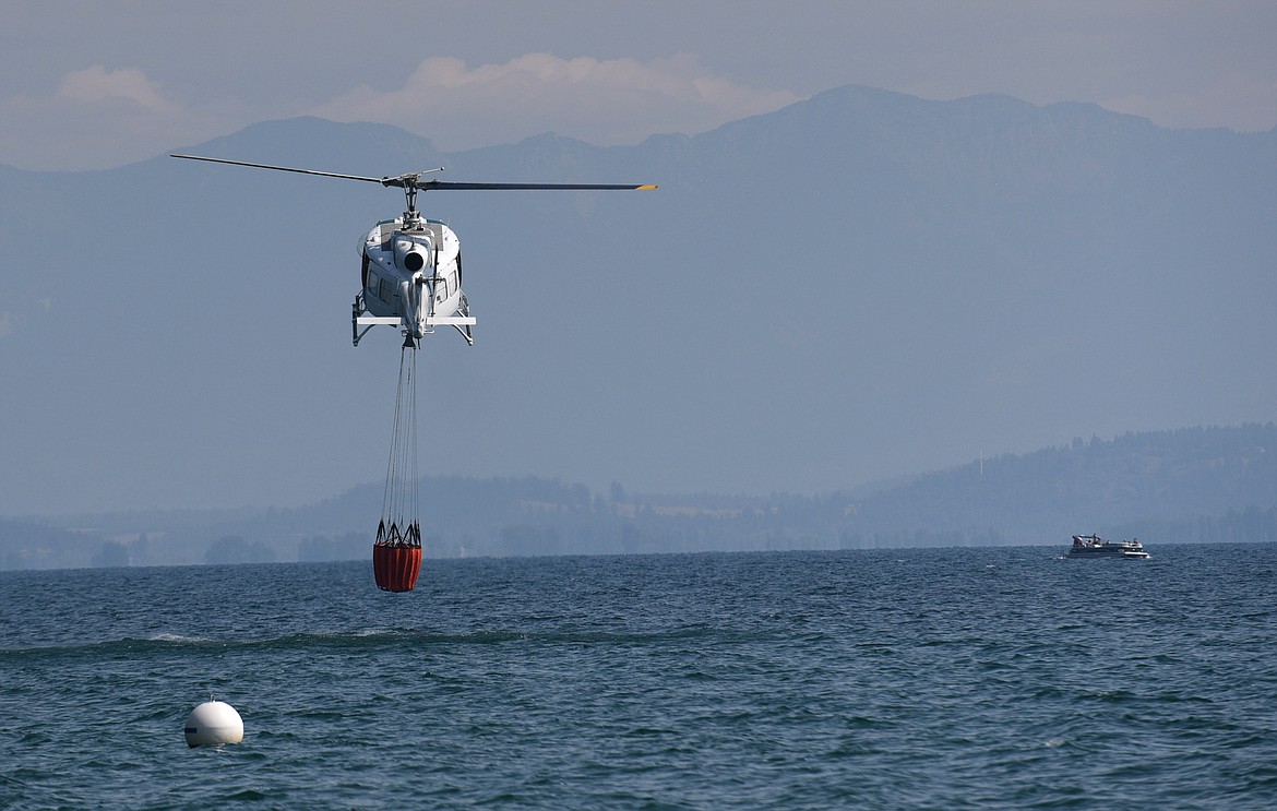 A helicopter fills its bucket with water from Flathead Lake to drop on the Bierney Creek Fire on Tuesday. (Aaric Bryan/Daily Inter Lake)