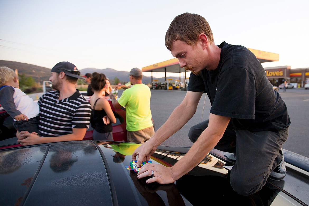 JAKE PARRISH/PressRay Cropper fastens a Maliki Wilburn memorium sticker to the rear window of Cropper's car on Monday at the Love's Travel Stop in Post Falls. More than 25 people gathered at the gas station before driving together to a candlelight vigil for the 17-month-old at Crowley Park in Spokane.