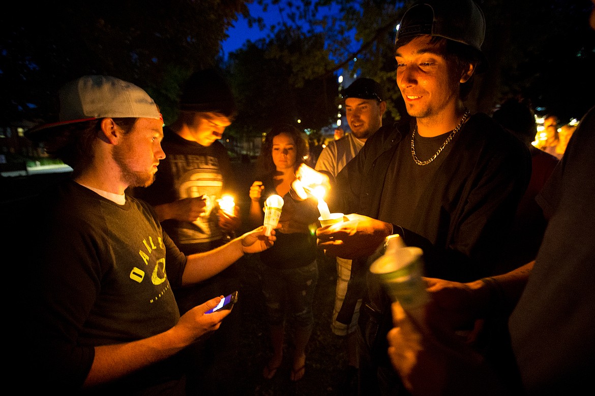 JAKE PARRISH/PressJesse Paschane, right, lights candles with his friends in memory of 17-month-old Maliki Wilburn on Monday at Crowley Park in Spokane.