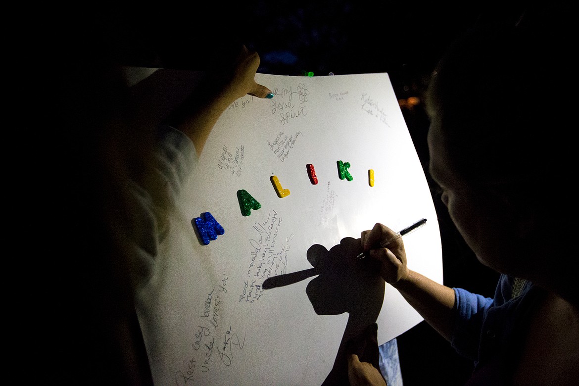 JAKE PARRISH/PressPeople sign goodbye wishes to Maliki Wilburn before a candlelight vigil for the 17-month-old boy Monday evening at Crowley Park in Spokane.