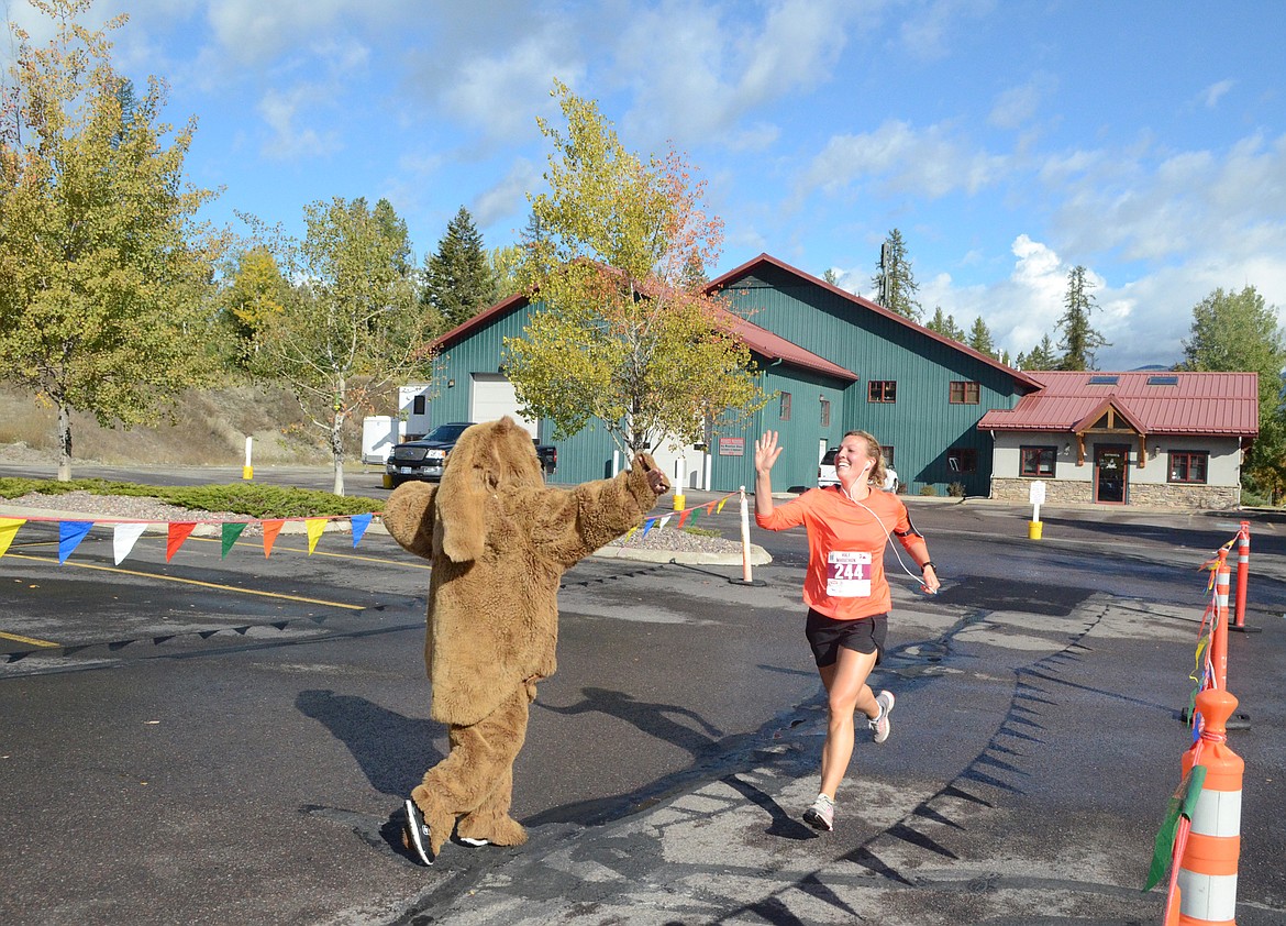 Maria Ployhar of Kalispell gets a high-five from a bear as she finishes the half marathon Sunday in the Two Bear Marathon. Heidi Desch / Whitefish Pilot