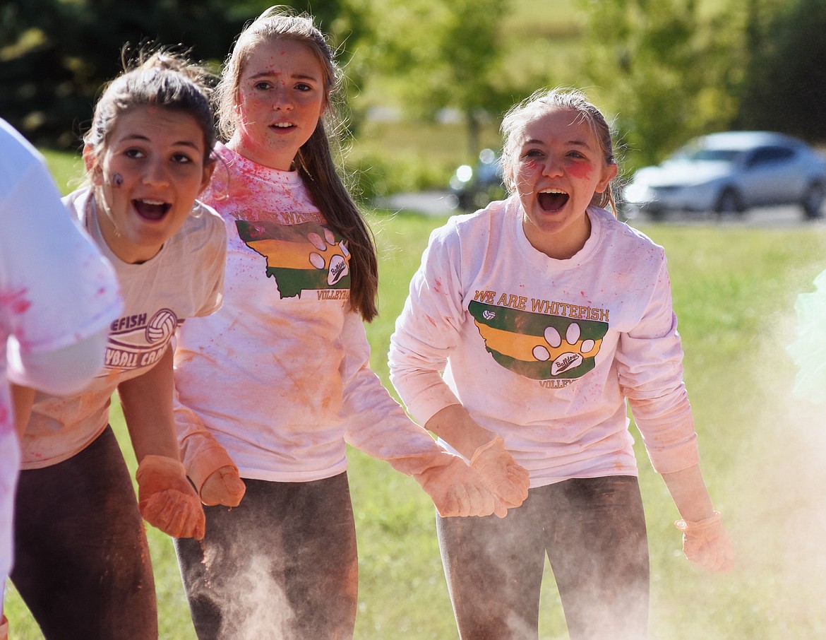 Members of the Whitefish High School volleyball team cheer on runners.