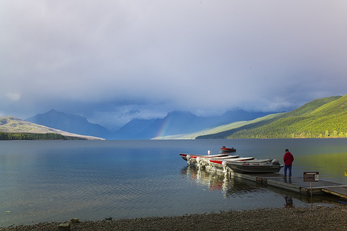 A man stands on the boat dock at Apgar as a rainbow sprouts from Lake McDonald Monday.