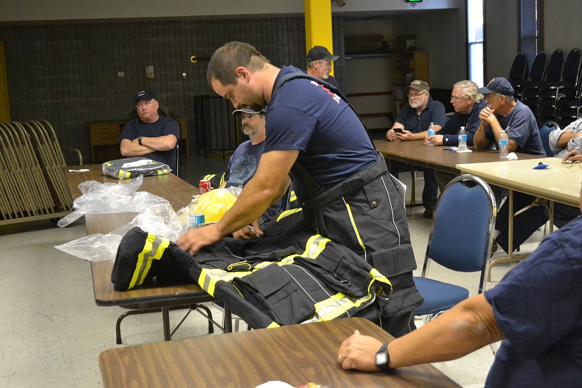 &#151;Photo by SARAH JENKINS
Matt Solt inspects the new suit designed to &#147;shake off&#148; any contaminated particles from a fire. The outer shell of the turnout is intended to come off at the scene to enable the the firefighter and vehicle to remain uncontaminated.