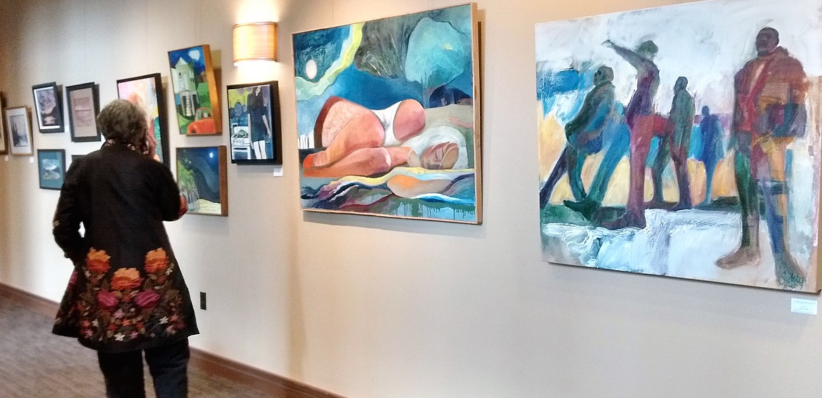 An individual looks at  works on display at a Pend Oreille Arts Council exhibit.