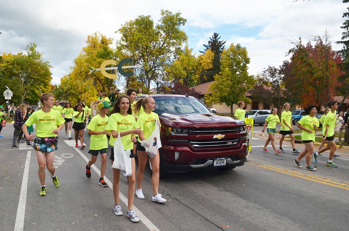 The Bulldog cross country team throws out candy Friday during the Whitefish High School homecoming parade.