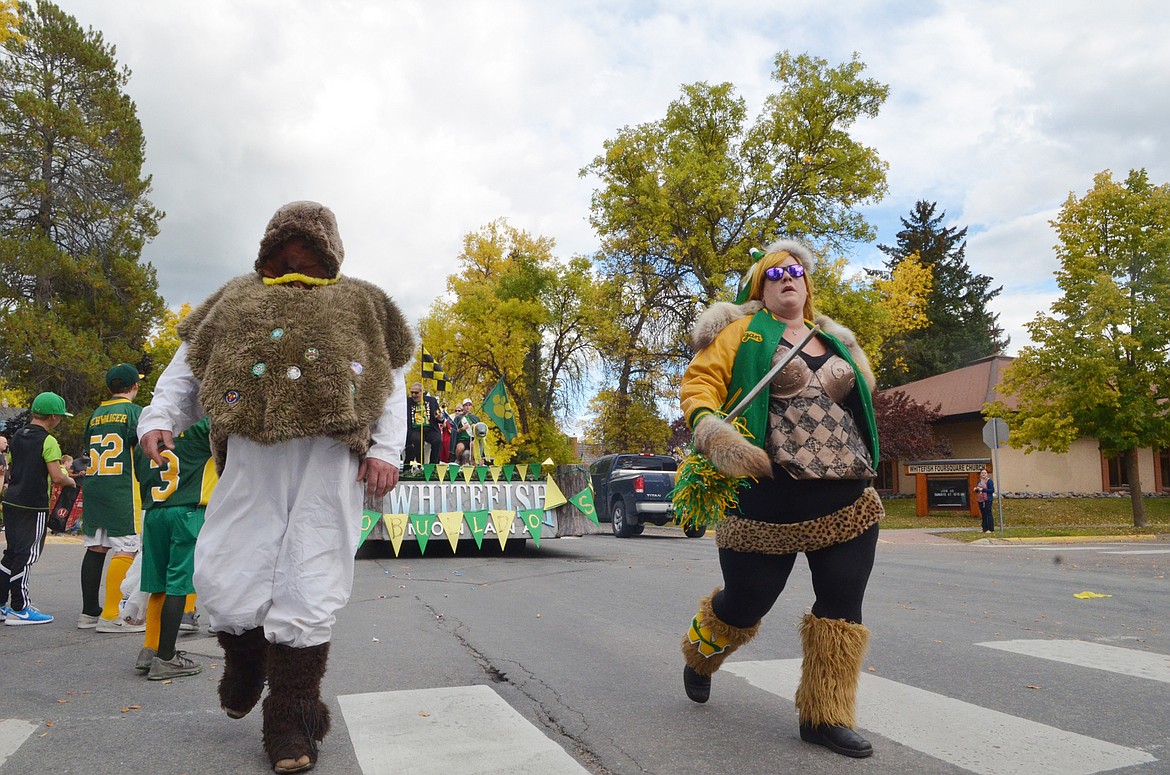 A yeti and a viking diva walk down Second Street Friday during the Whitefish High School homecoming parade.