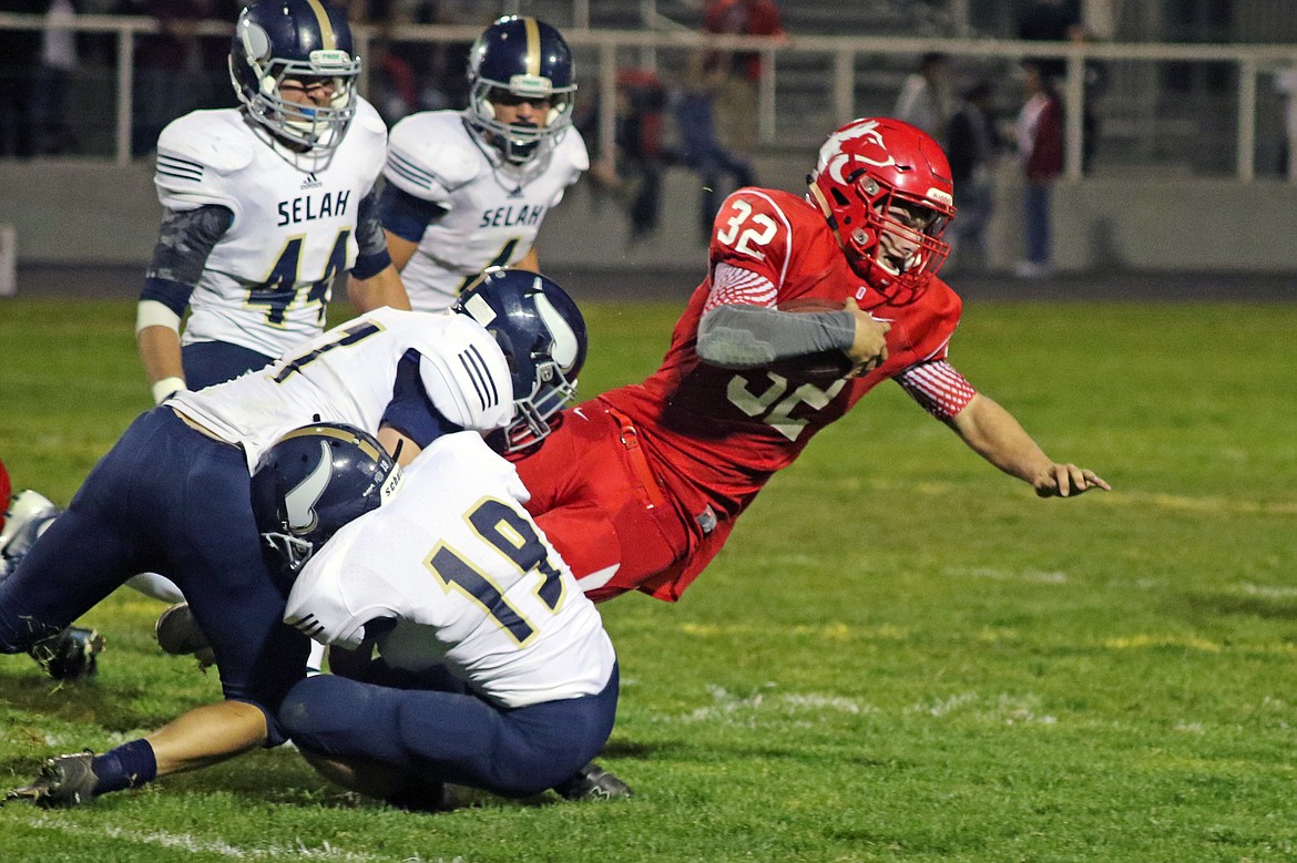 Bob Barrett PhotoTrevor Hilmes drags two Selah defenders with him as he falls forward. Huskies ground and pound Vikings 20-13.