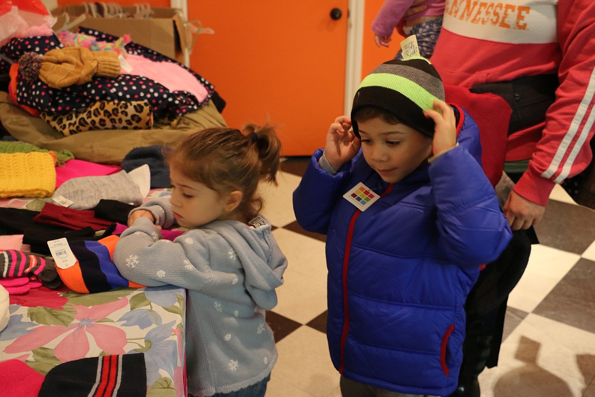 &#151; Photo by MARY MALONE
Brennan Odom, 5, tries on a new hat as his sister, 3-year-old Gwendolyn, looks through the pile trying to find the perfect one during the Coats 4 Kids distribution event at the Bonner Mall Wednesday evening, hosted by KXLY's Kris Crocker.