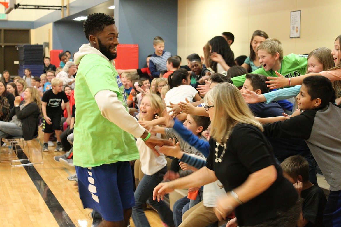 Charles H. Featherstone/Columbia Basin Herald.
Viking basketball player Zach Shepherd gives fifth graders at Sage Point Elementary School a round of high fives after a successful dunk.