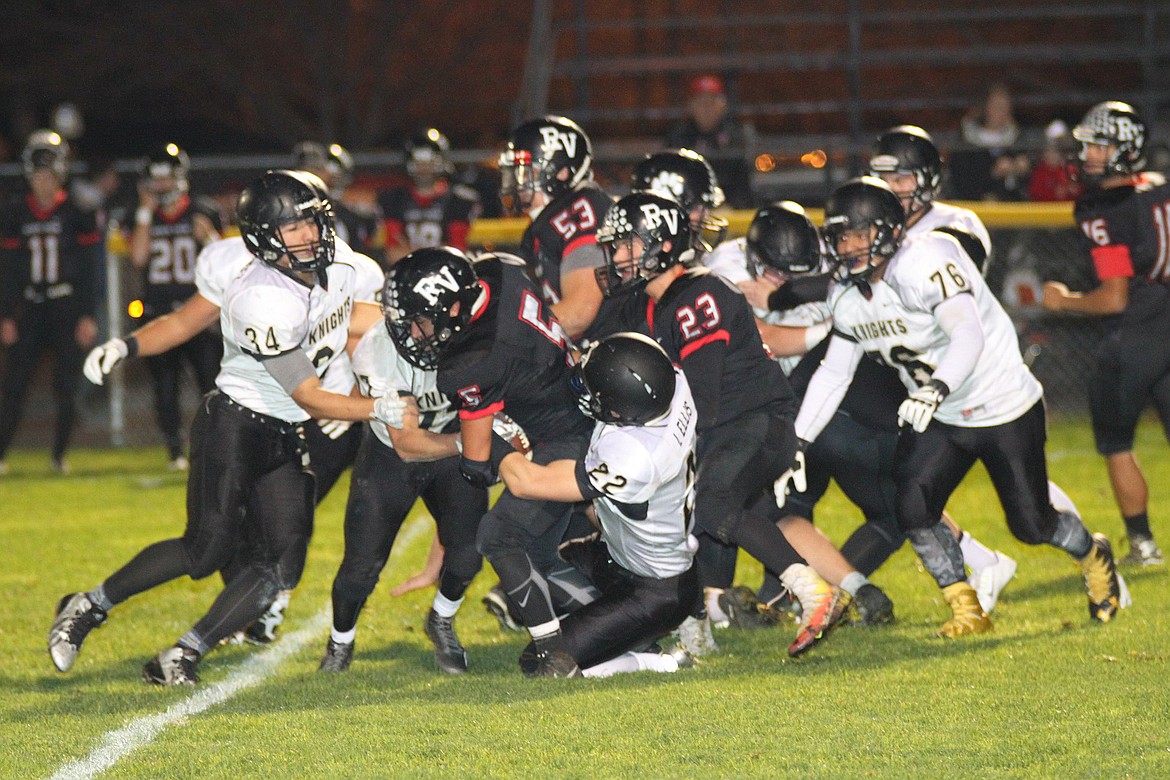 Pete Christensen Photo - Wyatt Allred, 72, and Isaac Ellis latch onto a River View ball carrier as Alonzo Hernandez, 34, and Juan Hernadez, 76, close in.