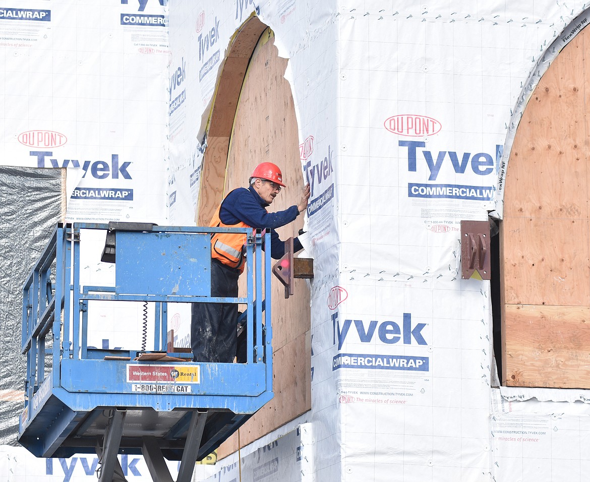 Standing in a lift, a crewmember works on the second floor archways of the new City Hall building. The building will be covered in red brick and will feature two prominent curved archways reminiscent of the historic City Hall building.