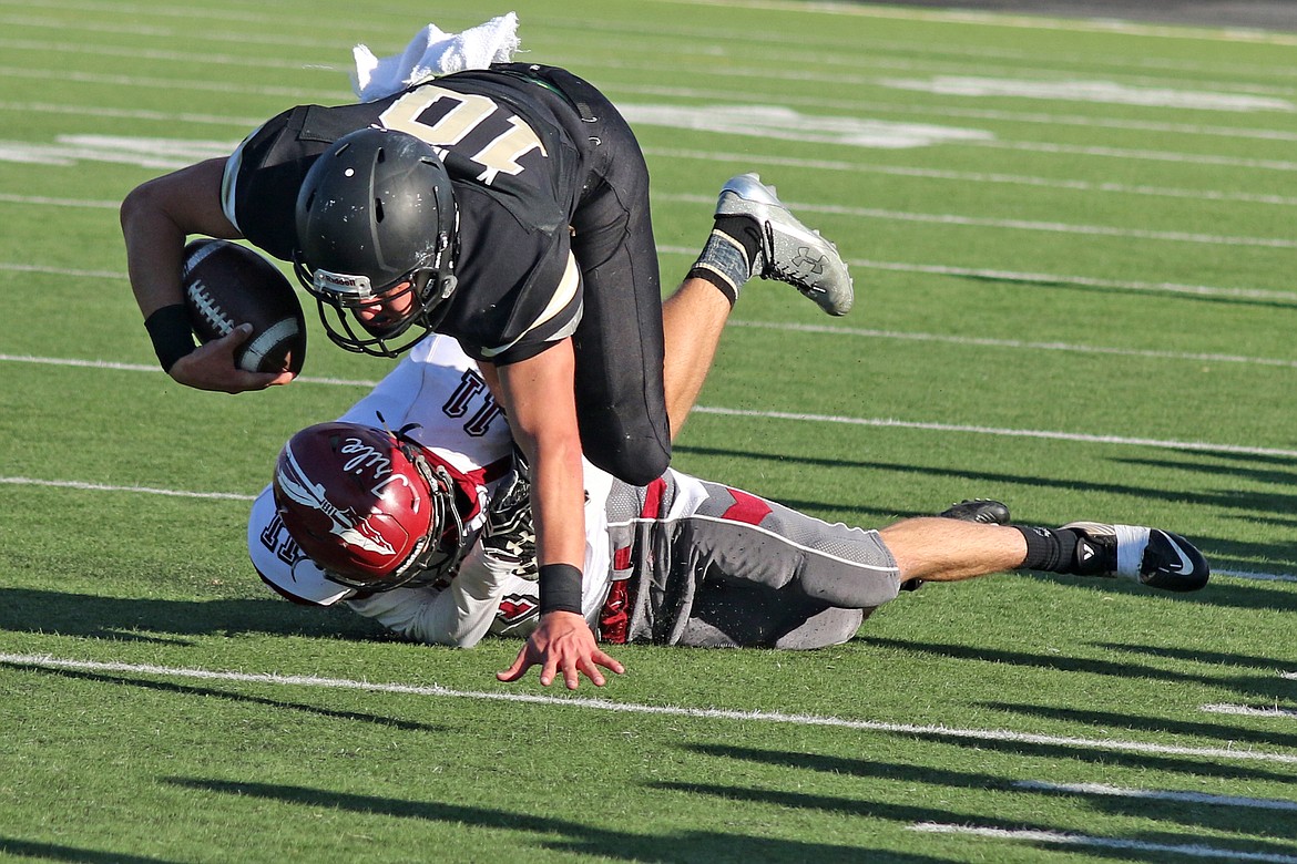 Bob Barrett Photo - A Colville defender tackles Royal's Kaden Jenks along the Royal sideline, but he pays a price when he's steamrolled by the 6-2, 215-pound quarterback.