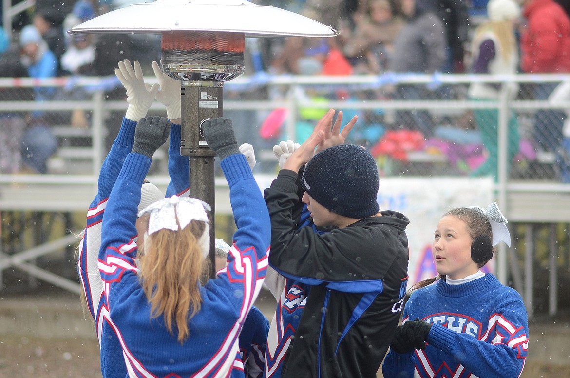 The cheerleaders warm their hands in the frigid conditions.