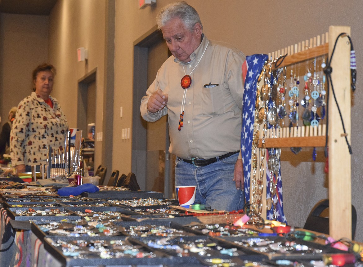 RAY RANDO picks out a piece of jewelry for a customer at the KwaTaqNuk Resort&#146;s Holiday Bazaar on Friday while his wife Cheryl Rando looks on. (Brett Berntsen/Lake County Leader)