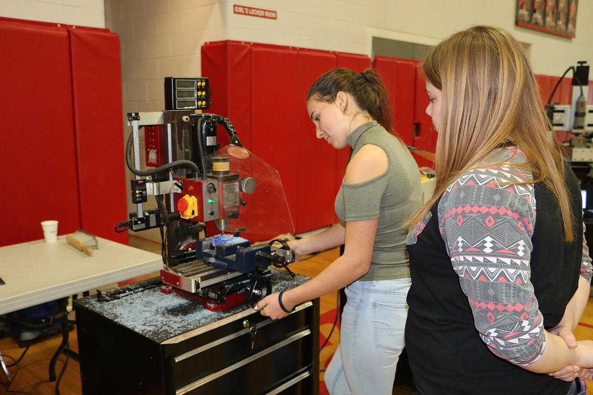 &#151; Photo by MARY MALONE
Sandpoint High School sophomore Megan Tylor watches as sophomore Sophie Slater machines a piece of tooling wax during the North Idaho College CTE Roadshow Friday at SHS.